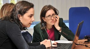 3 Frauen vor dem Laptop: eine gibt etwas ein, eine andere schaut konzentriert zu.