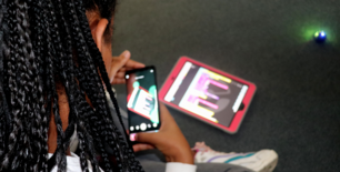 Mädchen fotografiert mit Smartphone selbst erstellten Ozoblockly-Code auf Tablet