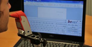 Mann bedient Bildschirmtastatur mit Mundmaus
