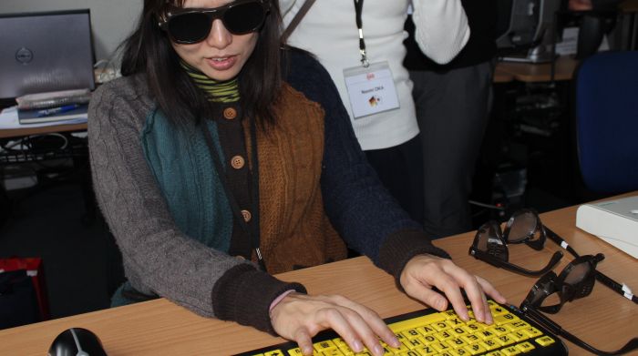 Teilnehmende der japanischen Delegation testet mit Sehbehinderungssimulationbrille Tastatur für Sehbehinderte