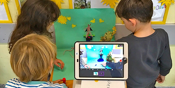 Kinder filmen mit Tablets einen Stop Motion Film vor selbstgebastelter Kulisse