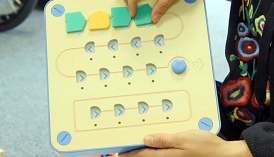 Hölzernes Steuerungsbrett von Cubetto mit farbigen Holzbausteinen als Code-Elemente
