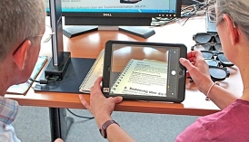 Frau nutzt iPad als Lupe um Dokument zu vergrößern