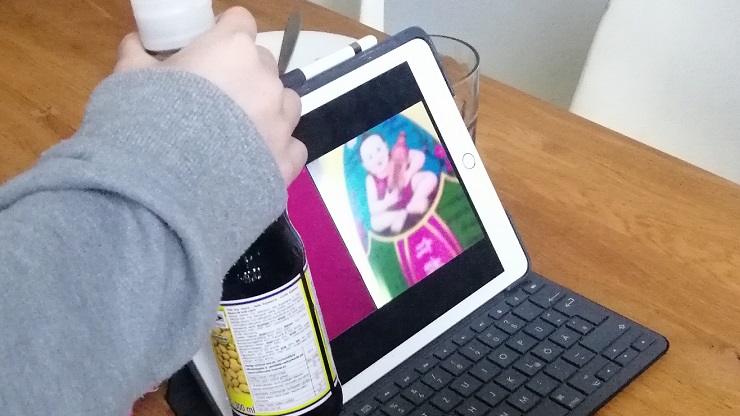 Kind hält Etikett einer Sojasoßenflasche mit asiatischen Motiv vor Tablet-Kamera